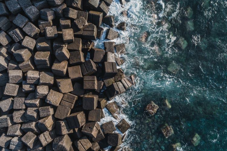 Waves from Atlantic Ocean crashing onto coastal Tetrapods seen from above, Tenerife, Spain
