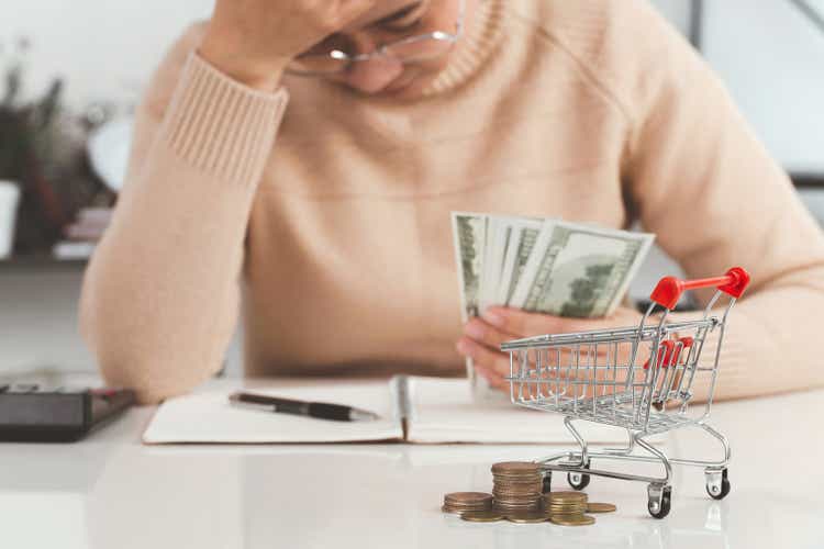 Women holding their forehead while having headache due to higher food prices from inflation.Rising food and grocery store prices and expensive daily consumer goods concept. The problem of inflation