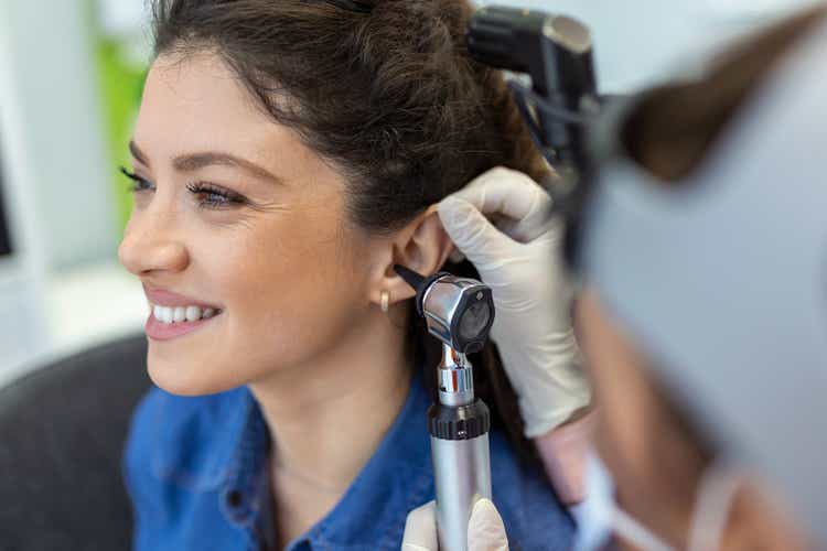 Close up of a female doctor carefully holding the ear of his patient to establish a clearer view of the inside of his ear, to see if he requires hearing aids at a modern clinic