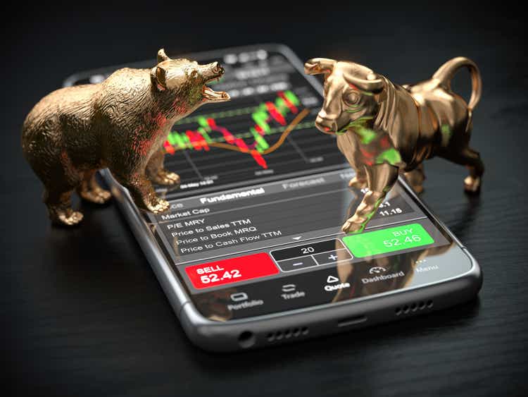 Gold bull and bear as stock market symbols on mobile phone with stock market data app on screen.