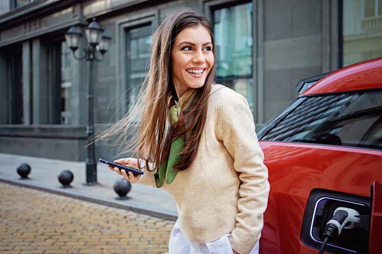 Portrait of woman charging her electric car