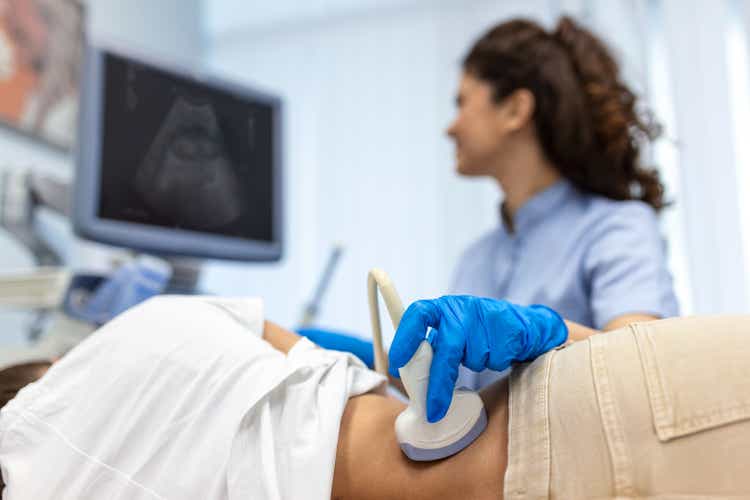 Doctor conducts ultrasound examination of patientv kidneys. Internal organs ultrasound concept. female"s lower back diagnosis carried out with the use of an ultrasound