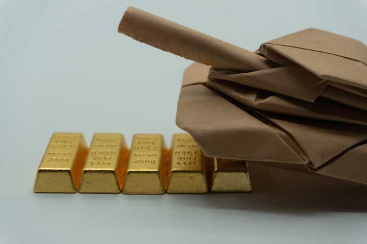 Paper-folded tank rolling over gold. An allusion to the huge military expenditure required for war. It drains the country"s coffers. The international price of gold.trade intension.