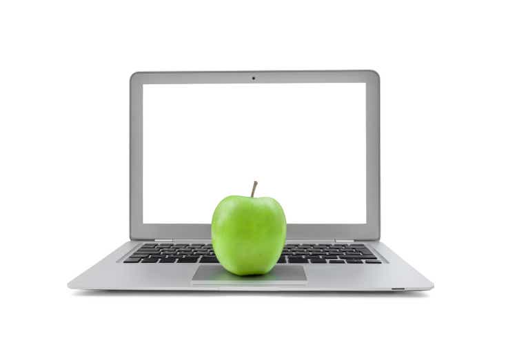 Laptop with blank screen and green apple isolated on white background