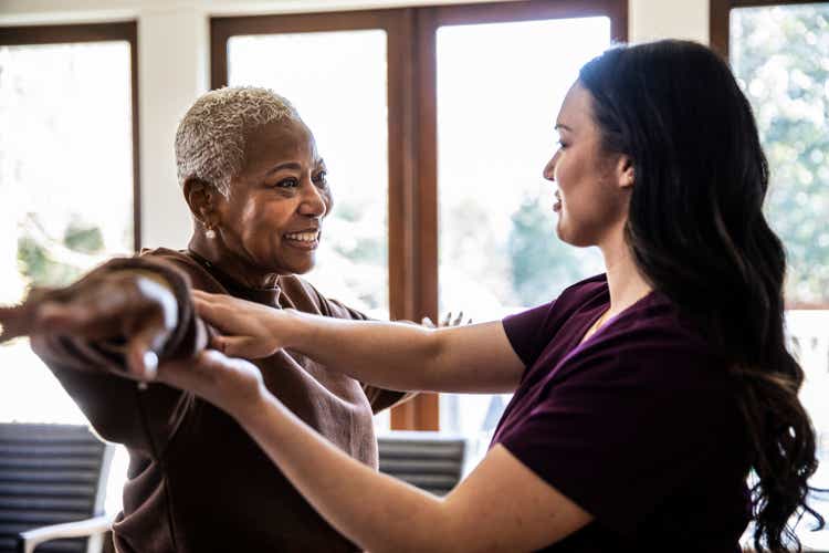 Nurse helping senior woman with physical therapy in her home