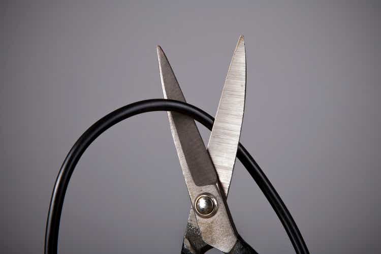 Close up of metal scissors cutting black wire