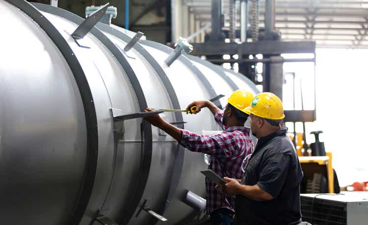 Two multiracial men working in a metal manufacturing factory