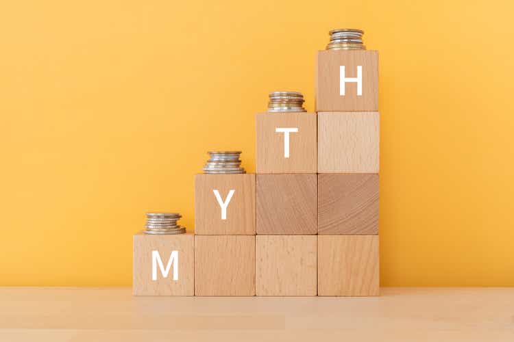 Wooden blocks with "MYTH" text of concept and coins.
