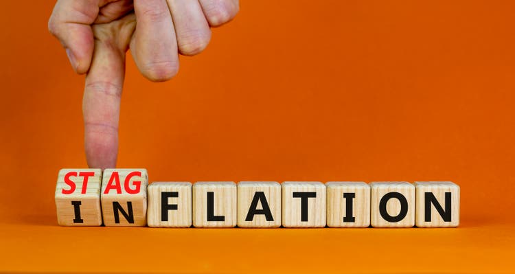 Stagflation or inflation symbol. Businessman turns cubes and changes the concept word inflation to stagflation. Beautiful orange background, copy space. Business stagflation or inflation concept.