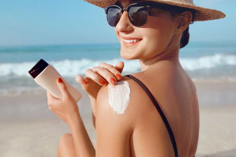 Girl Using Sunscreen to Skin. Beautiful Woman in Bikini Applying Sun Cream on Tanned Shoulder. Sun Protection. Skin and Body Care.