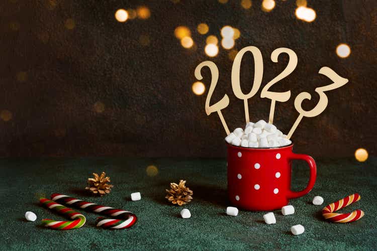 Christmas or New Year 2023 concept. Red mug with hot chocolate and marshmallows and golden numbers 2022, copy space