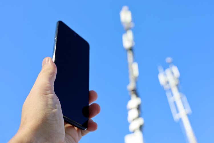 Smartphone in male hand on background of cell towers