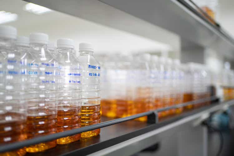Petroleum lubricating oil in the plastic bottle arranged neatly on the shelf in the laboratory. Automotive and industrial oil technology concept
