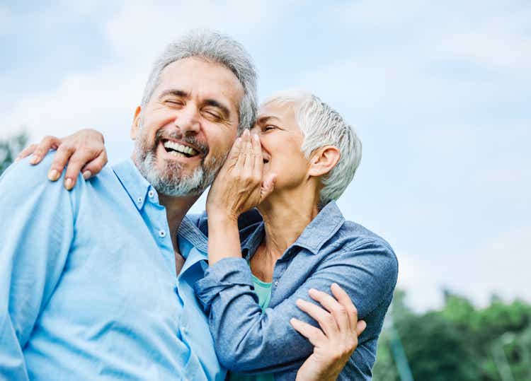 senior couple happy elderly love together retirement lifestyle smiling man woman mature ear gossip secret whispering whisper