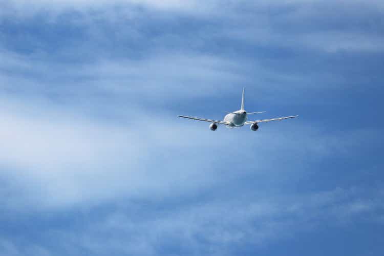 Avión volando en el cielo azul sobre el fondo de las nubes blancas, vista trasera