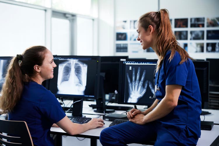 Two female healthcare professionals looking at x-ray scans