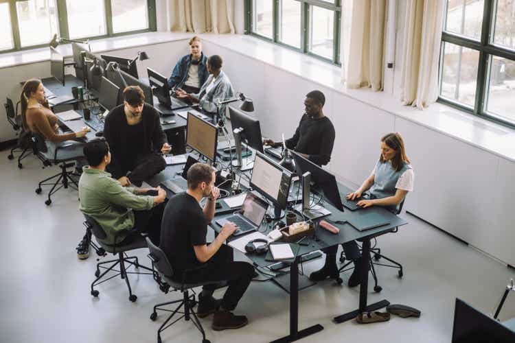 High angle view of male and female programmers working on computers at desk in office