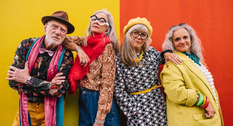 Active elderly people standing together against a colourful wall