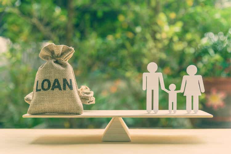 Family finance / financial loan and risk management concept : Loan bags, white acrylic cut (dad, mom, son) on a basic balance scale.