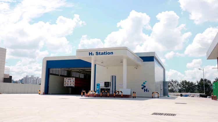 view of a modern hydrogen refueling station for hydrogen cars with a large parking lot and located on the outskirts of a city.