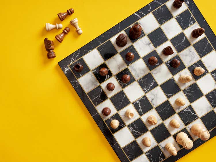 Top view of chessboard with chess pieces on yellow background