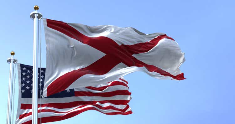 The flags of the Alabama state and United States of America waving in the wind.
