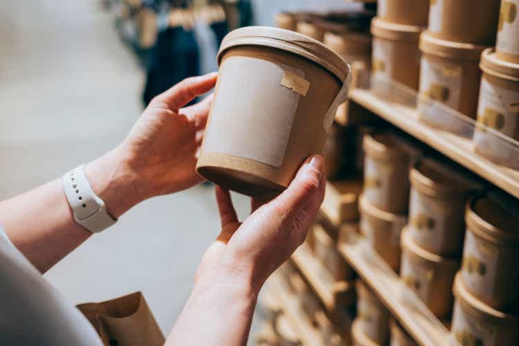 A Close Up Shot Of An Unrecognizable Woman In A Shop Holding A Biodegradable Package Of Some Product Deciding Whether To Buy It Or Not