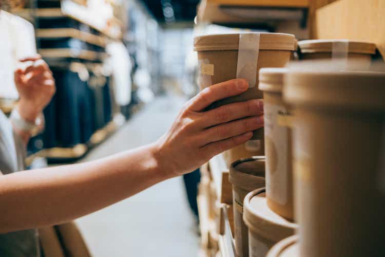 A Close Up Shot Of An Anonymous Caucasian Woman In A Shop Holding A Biodegradable Package Of Some Product Deciding Whether To Buy It Or Not