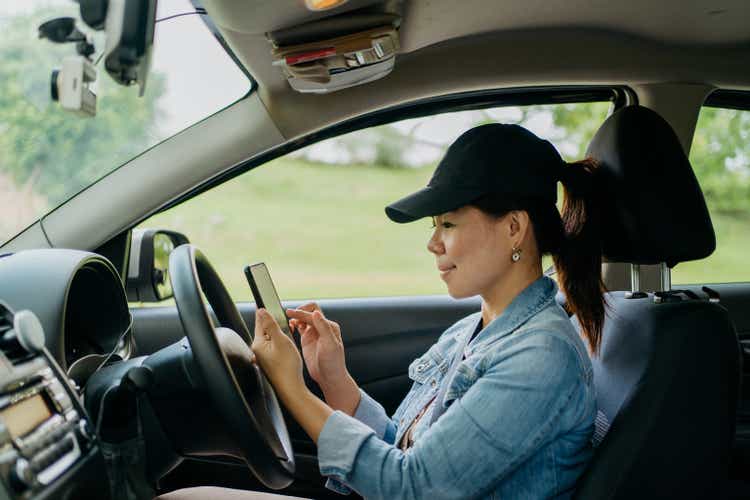 Female driver using smartphone in car