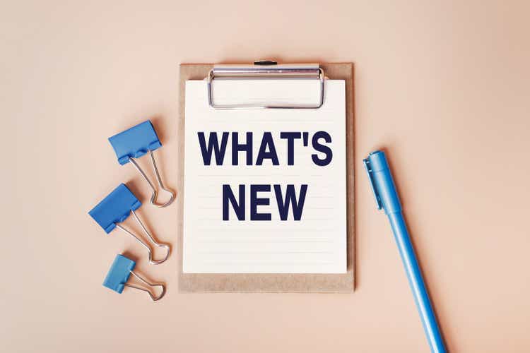 WHAT"S NEW - words written in a notebook. Question for Social media, Blog post. Top view image of notebook and with many paper clips and blue pen on beige background