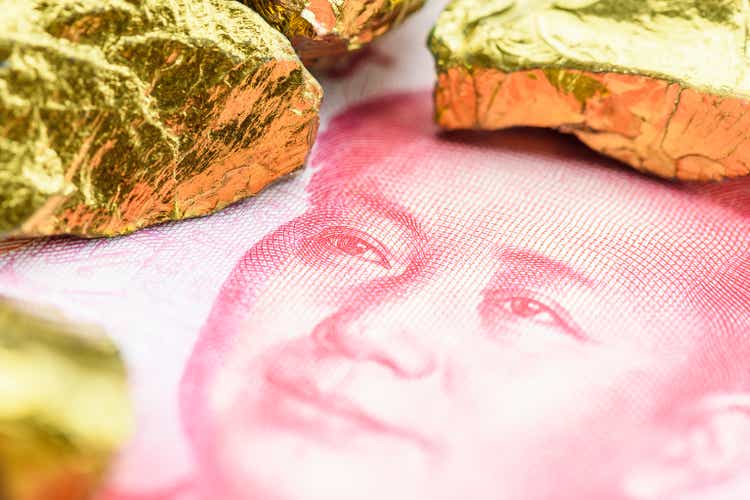 Precious metals and currency investment concept : Gold colored iron ore on a China yuan money.