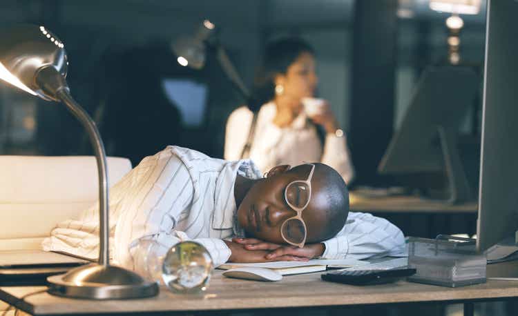 Shot of a young businesswoman sleeping at her desk while working late in a modern office