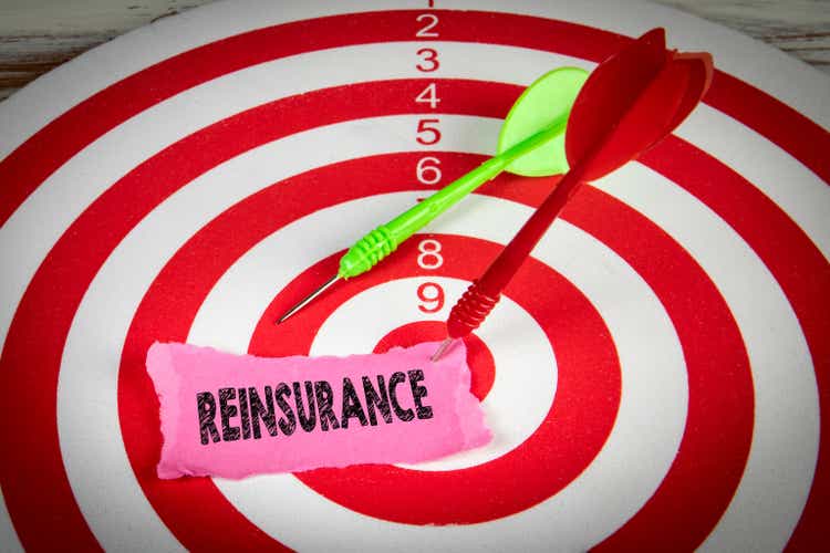 REINSURANCE. Piece of paper and darts on a red target