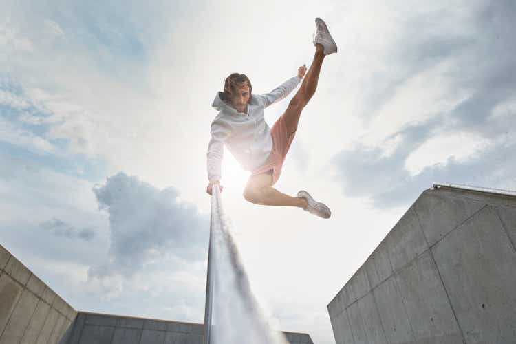 Young male ballet dancer jumping against sky