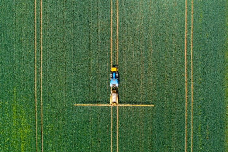 Aerial view of farming tractor crop sprayer in the countryside