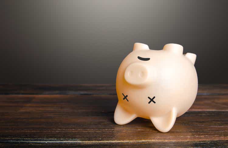 Dead piggy bank lies upside down. Economic depression. Financial crisis, end of savings, bankruptcy. Devaluation, inflation. Impoverishment. Refinancing restructuring of debts.