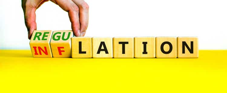 Inflation or regulation symbol. Businessman turns cubes and changes the word inflation to regulation. Beautiful yellow table, white background, copy space. Business, inflation or regulation concept.