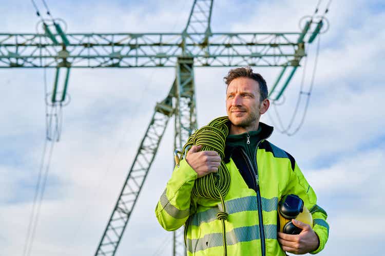 Portrait of an electrical engineer in front of high voltage power transformer substation