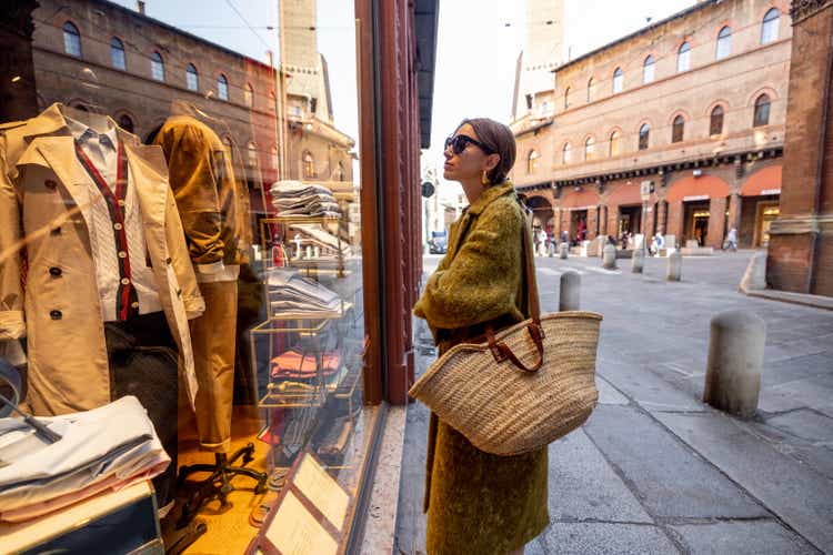 Woman near the showcase of the shop with luxury clothes on street in Bologna