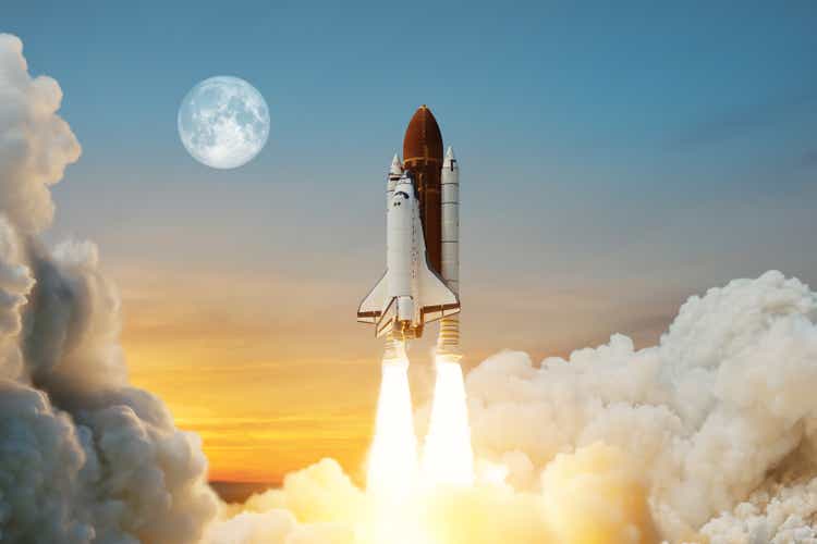 Spaceship lift off. Space shuttle with smoke and blast takes off into space on a background of sunset with a full moon.