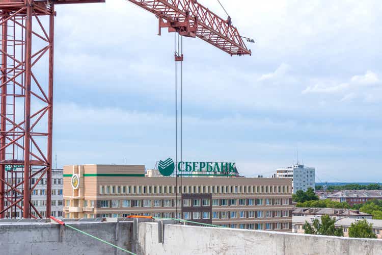 Construction red tower crane works against the backdrop of the Sberbank office