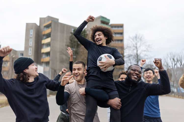 Winning football team cheering on playing field