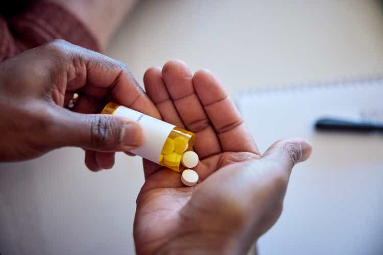 African American man pouring medications out of a bottle into his hand.