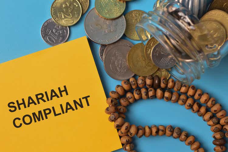 Top view of coins, rosary beads and memo note written with SHARIAH COMPLIANT.