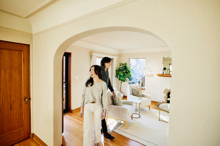 Wide shot of smiling couple walking into home for sale