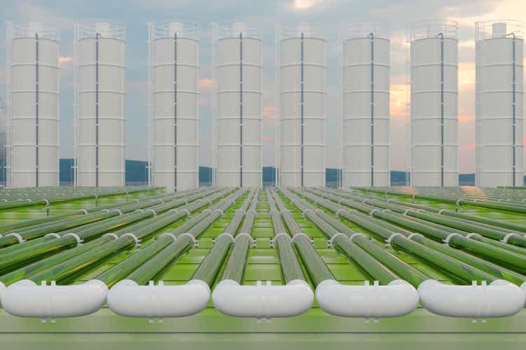 Tubular Algae Bioreactors Fixing CO2 To Produce Biofuel As An Alternative Fuel With Storage Tanks And Blue Sky Background
