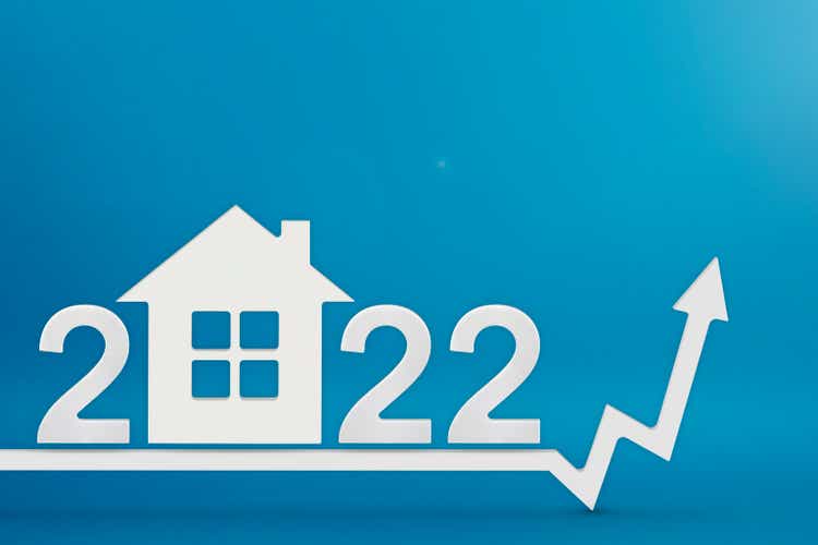Real estate value in 2022. Rising costs of construction, insurance, rent and mortgages. inflation and rising prices. Model of a house on a blue background. Numbers 2022 on up arrow