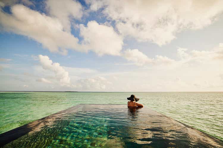 Extreme wide shot of mature woman relaxing in infinity pool