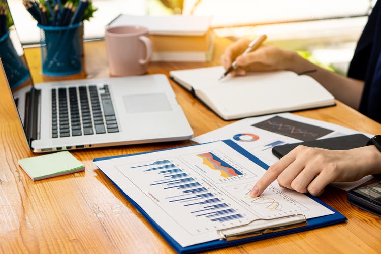 Businessman with pen pointing to graph, financial data, research, develop, market report. Strategic planning, analyzing, calculating financial accounts with calculator and laptop in the office.