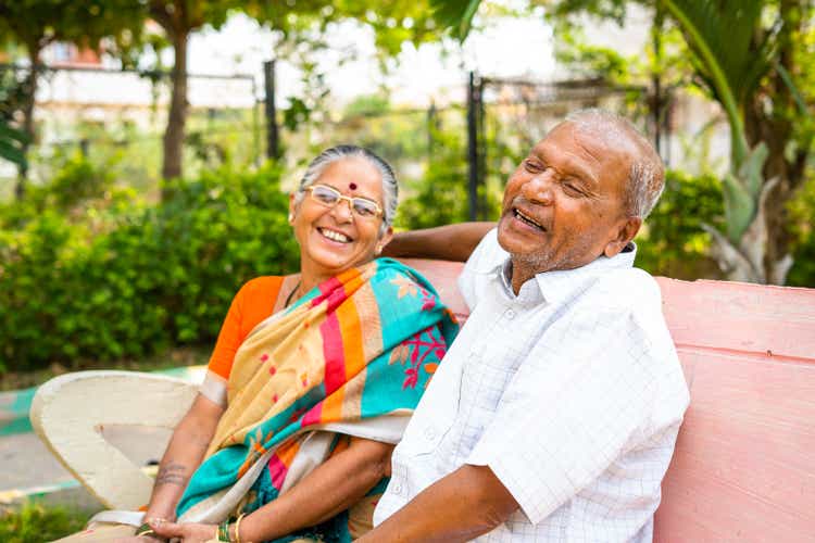 laughing Senior couple while talking with each other at park - concept of friendship, enjoyment and relaxation